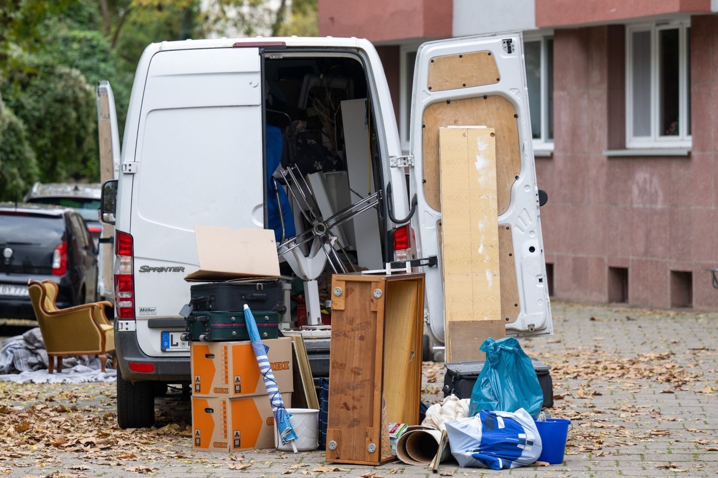 Möbel und Umzugskartons stehen vor einem Transporter an einem Wohnhaus in Leipzig. (Symbolbild)