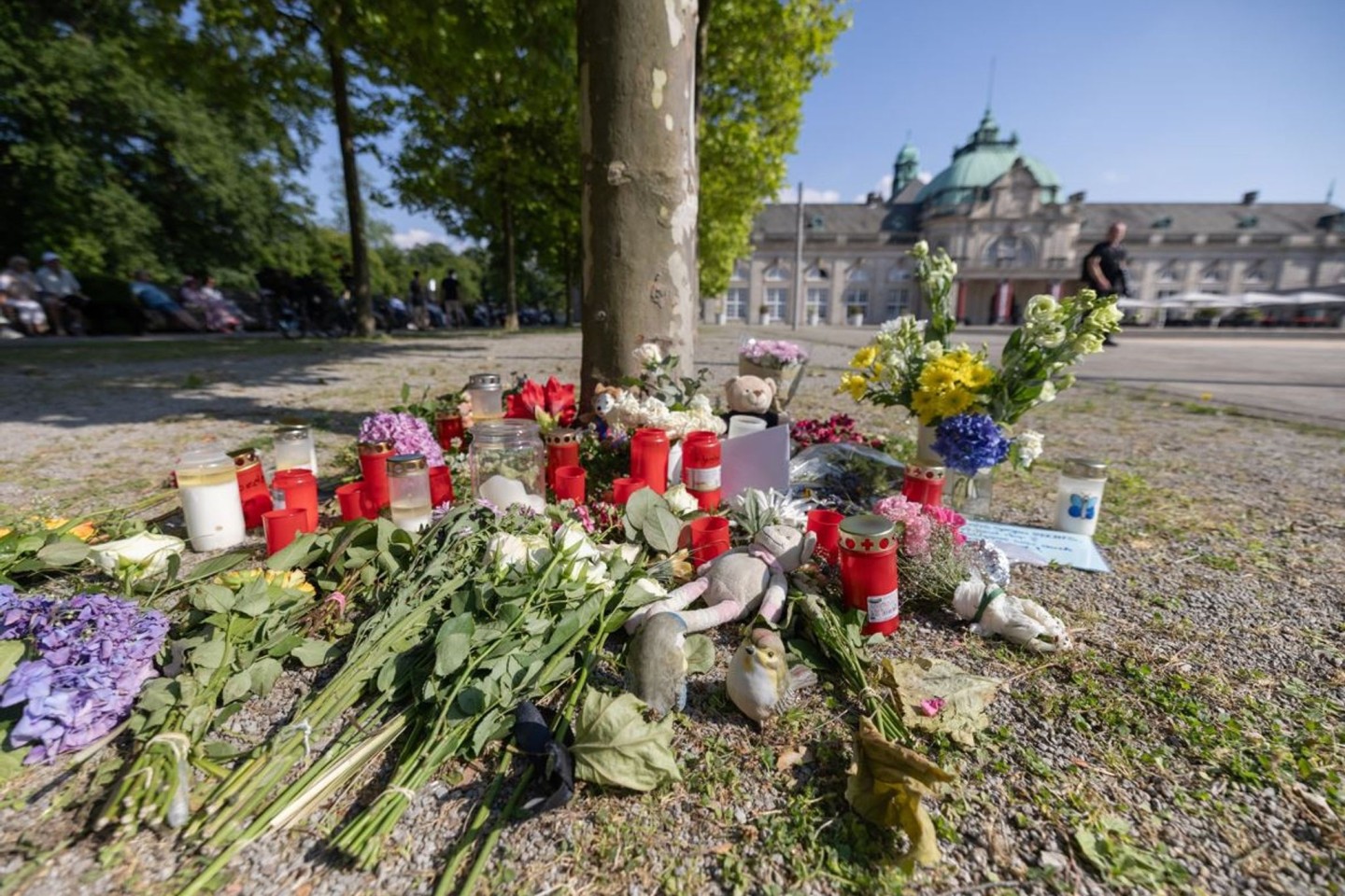 Blumen, Kerzen und handgeschriebene Trauerbekundungen an einem Baum im Kurpark Bad Oeynhausen.